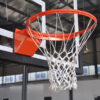 Orange basketball hoop with white net mounted to a backboard in an indoor gym facility.