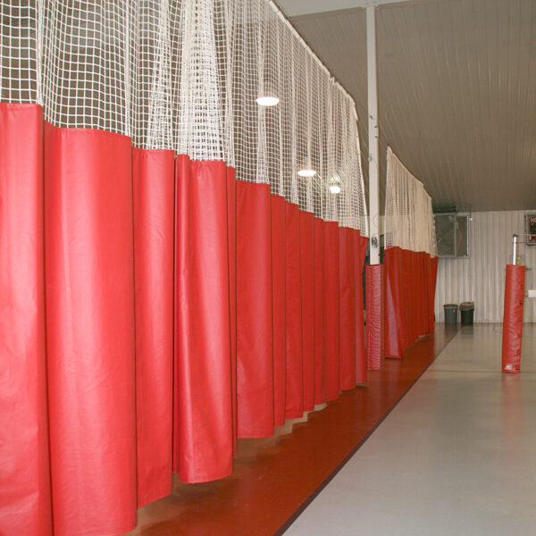 Row of red hanging punching bags along a gym hallway.